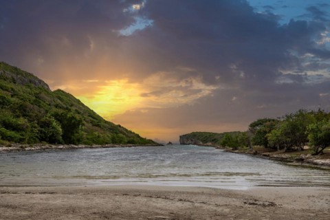 Rocky coast, long bay by the sea at sunset. Dangerous view of the Caribbean Sea. Tropical climate