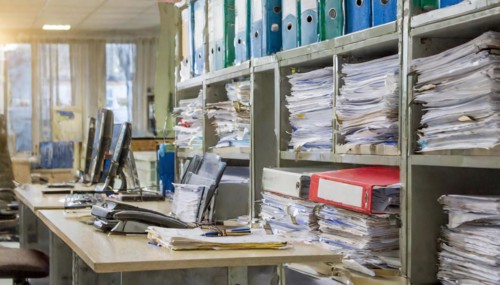 Overcrowded workplace with many folders and piles of paper in an office, symbolism bureaucracy, AI