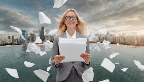 Woman in suit holding a sheet of paper while other papers fly around her in the wind, symbol