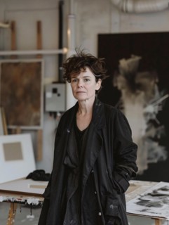 An artist stands contemplatively in her studio, surrounded by pieces of art, AI generated