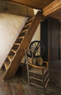 Antique rocking chair and spinning wheel next to Miller's stairs in master bedroom on upstairs