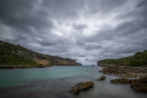 Rocky coast, long bay by the sea at sunset. Dangerous view of the Caribbean Sea. Tropical climate