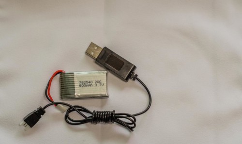 A USB cable connected to a lithium polymer battery on a white surface, in South Korea