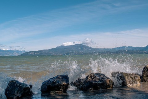 Splashing waves hitting rocks on the shore of Lake Garda, Sirmione, Lake Garda, Italy, Europe