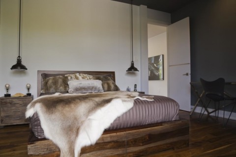 Queen size wooden base bed covered with fur pelt throw in guest bedroom inside luxurious home,