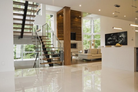 Wood, metal and glass staircase leading to living room with creamy beige L-shaped leather sofa