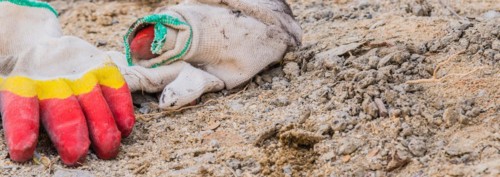 Worn work gloves discarded among construction debris and dirt, in South Korea