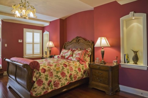 Wooden sleigh bed and night table in master bedroom on upstairs floor inside elegant style home,