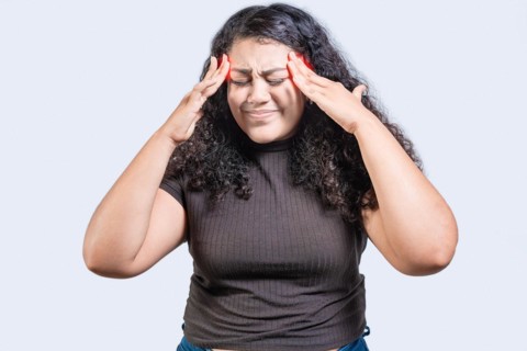 Young woman with headache isolated. Girl suffering from migraine holding head. Headache concept