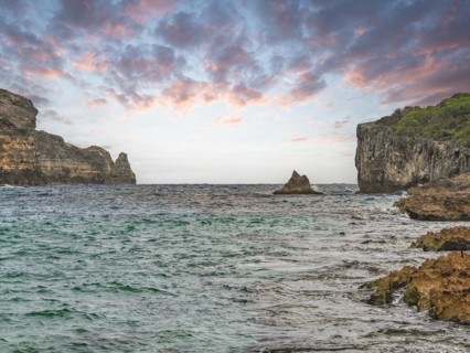 Rocky coast, long bay by the sea at sunset. Dangerous view of the Caribbean Sea. Tropical climate