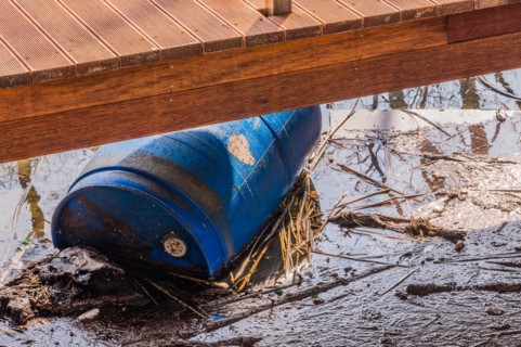 A raised deck beside a creek with a blue barrel partially hidden underneath, in South Korea