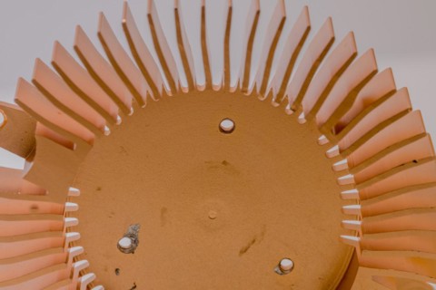 Closeup of copper heat sink fins and fan mounting surface with chipped screw holes