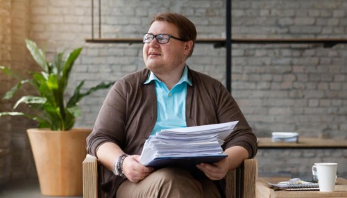 Relaxed man with pile of documents sits smiling in the office, symbol bureaucracy, AI generated, AI