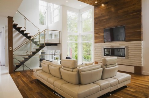 Living room with creamy beige colored L-shaped leather sofa and gas fireplace inside luxurious