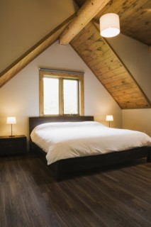 King size bed in master bedroom on upstairs floor inside contemporary style log home, Quebec,