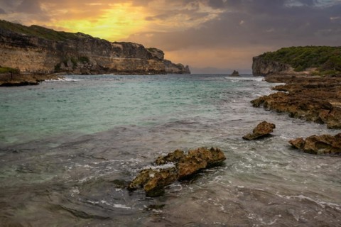 Rocky coast, long bay by the sea at sunset. Dangerous view of the Caribbean Sea. Tropical climate
