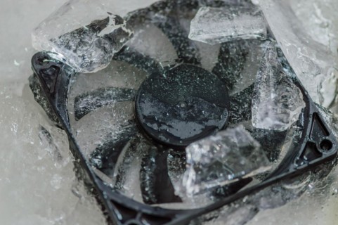 Closeup of computer case fan frozen in block of ice. Concept keep your computer cool