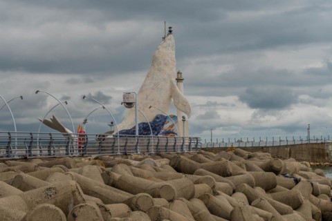 Mosaic fish sculpture on the harbor edge with street lamps and cloudy skies, in Ulsan, South Korea,