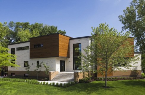 Beige stone with brown stained cedar wood modern cubist style residential home facade in spring,