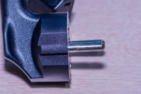 Closeup of computer power cord plug that plugs into electrical socket