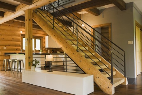 Kitchen with white wooden cabinets, metal bar stools and wooden log stairs with black wrought iron