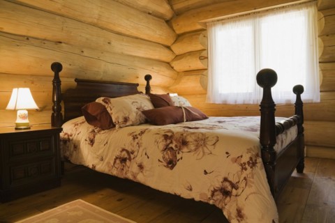 Antique four poster queen size bed with floral motifs bedspread in guest bedroom inside handcrafted