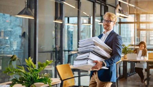 Cheerful businessman carrying a large pile of documents in the office, symbol bureaucracy, AI