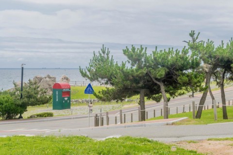 Scenic view of a road with sea and sky in the distance and trees surrounding a post box, in Ulsan,