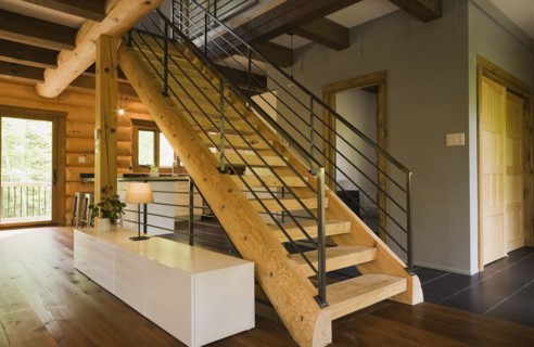 Wooden log stairs with black wrought iron railings and long cabinet table inside contemporary style