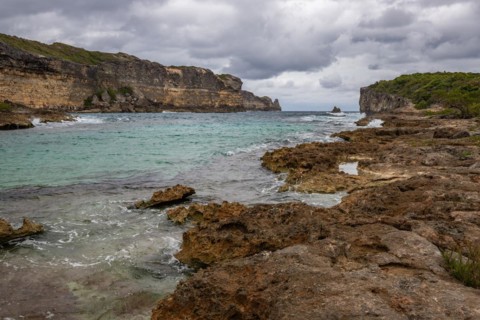 Rocky coast, long bay by the sea at sunset. Dangerous view of the Caribbean Sea. Tropical climate