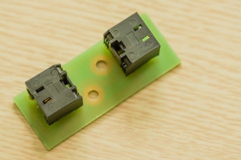 Two black plastic electrical connectors on a green circuit board, in South Korea