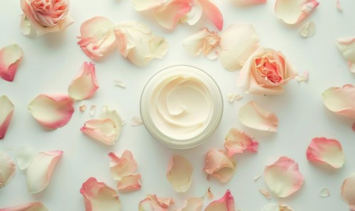 Blank creme jar mockup encircled by pastel flower petals on a white background, top view AI