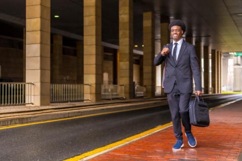 Horizontal photo with copy space of an african architect holding computer bag and drawings tube