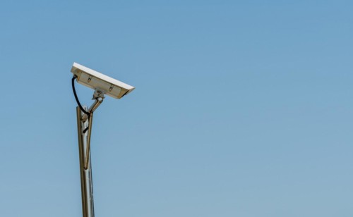 CCTV camera on shinny chrome plated pole against clear blue sky in South Korea