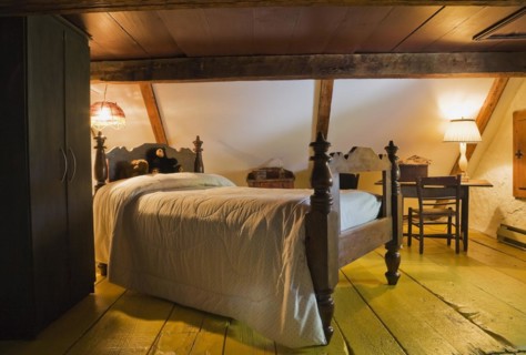 Antique wooden four-poster single bed and armoire in bedroom on upstairs floor inside old 1785