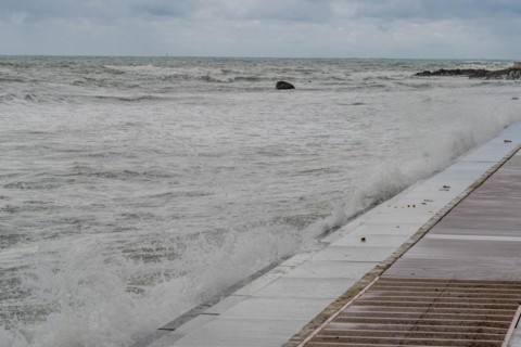 Waves crash against a sea wall creating whitecaps under an overcast sky, in Ulsan, South Korea,
