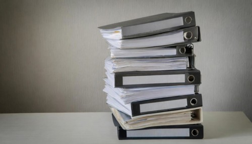 A high pile of files on a table symbolises a large workload, symbolism bureaucracy, AI generated,
