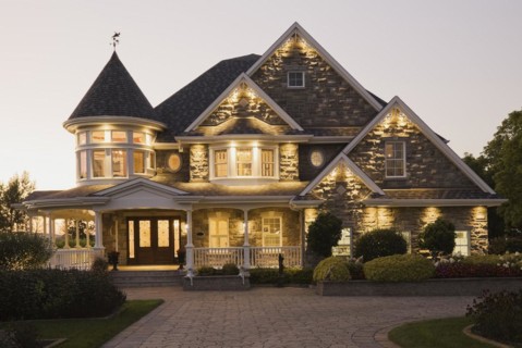 Elegant grey stone with white trim and blue asphalt shingles roof Victorian home facade at dusk in