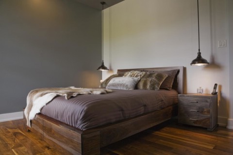 Queen size wooden base bed covered with fur pelt throw in guest bedroom inside luxurious home,