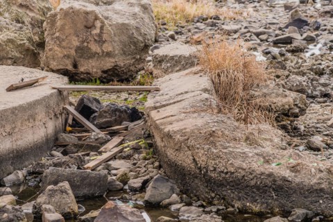 Dry stream bed showing damaged concrete structures and scattered rocks, in South Korea