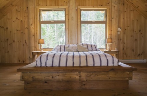 King size bed with wooden frame in master bedroom on upstairs floor inside handcrafted Eastern