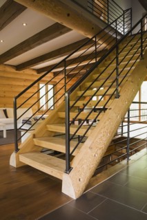 Wooden log stairs with black wrought iron railings and white cotton cloth upholstered sofas in