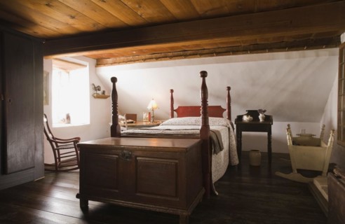 Double four-poster bed and old wooden storage chest in master bedroom on upstairs floor inside old