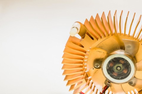 Closeup of round copper heat sink and plastic fan assembly on white background