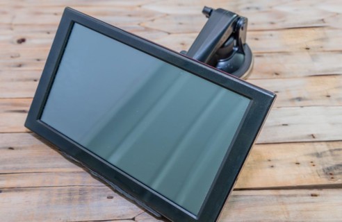 Front view of automobile navigation with attached mounting arm on wooden table