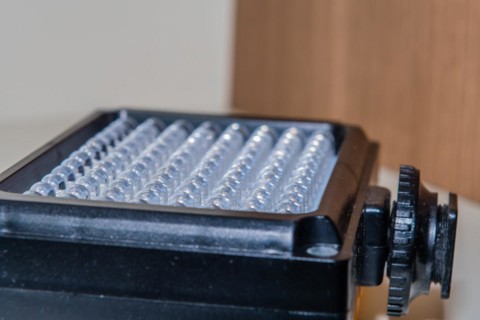 Closeup of LED continuous photographic light sitting on book shelf at home. Selective focus on