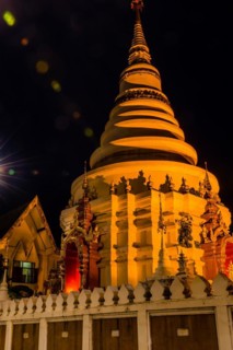 Illuminated temple with golden lights stands out against the dark night, in Chiang Mai, Thailand,