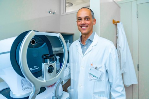 Portrait of an ophthalmologist in an innovative clinic standing next to a laser machine to treat