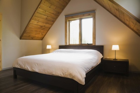 King size bed in master bedroom on upstairs floor inside contemporary style log home, Quebec,