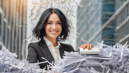 Happy young businesswoman uses a paper shredder in the modern office, symbol bureaucracy, AI